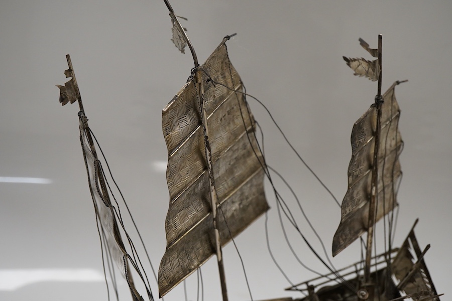 A pair of modern silver fighting cocks, import marks for Sheffield, Assay Office, Sheffield, 1977, height 68mm, together with a Chinese white metal miniature model of a ship, on a carved hardwood base, overall height 20.